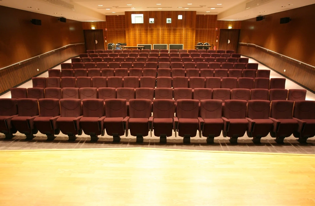 Reference image: an empty auditorium with rows of seats facing a stage
